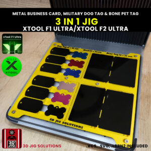 A top-down view of the xTool F1 Ultra 3-in-1 Jig loaded with sample metal business cards, bone tags, and military dog tags.
